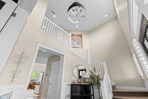 Two-story entryway featuring a vaulted ceiling and a chandelier