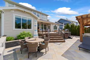Expansive outdoor living area featuring a multi-level paver patio, composite deck with black metal railings, and a built-in outdoor spa