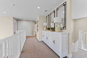 Carpeted hallway featuring a white decorative console cabinet with carved detailing