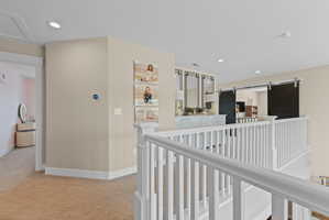 Upper-level landing featuring neutral carpeting and white railing