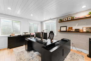 Dedicated room featuring wood-finish flooring, two window wells, recessed lighting, and a paneled ceiling