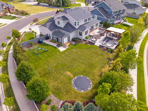 Expansive backyard featuring a manicured lawn, established landscaping, a multi-level paved patio, a pergola-covered outdoor living area, and a built-in spa