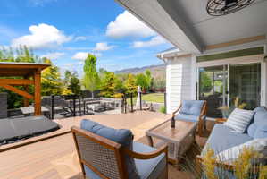 Expansive outdoor living area featuring a covered patio, a wood-finish composite deck, and a built-in hot tub with a wooden pergola