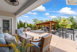 Expansive outdoor living area featuring a covered patio, composite deck, and hot tub