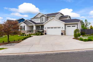 Modern residence featuring a multi-tone exterior with board and batten siding, stone accents, and dark shingle roofing