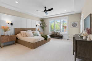Recessed lighting illuminates a tray ceiling and a modern ceiling fan