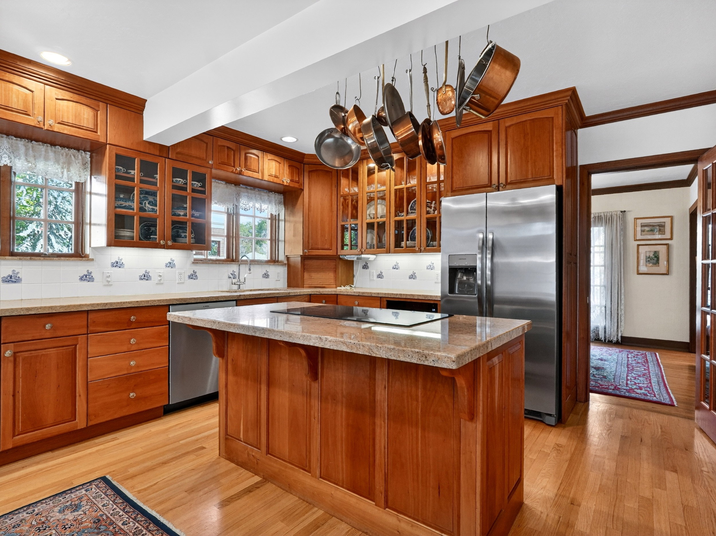 Kitchen featuring wood cabinetry, a central island with an integrated cooktop, granite countertops, and wood-finish flooring