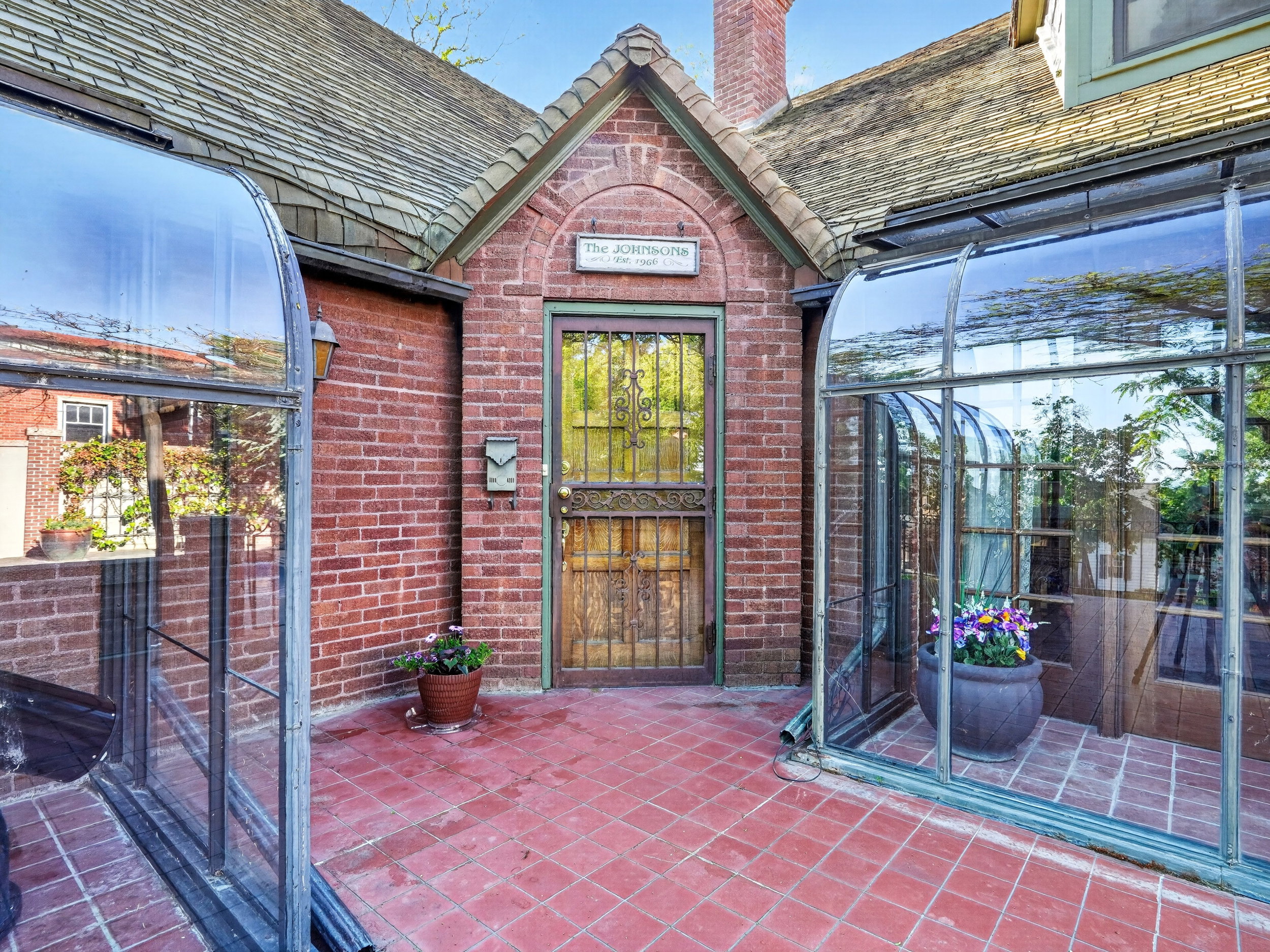 Brick exterior with arched entry featuring a wood-finish door.