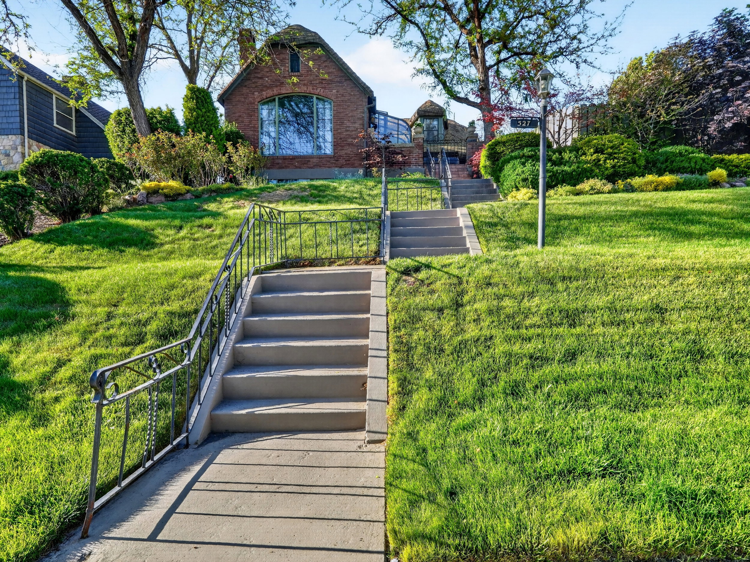 Brick exterior residence set on a terraced lot with a manicured lawn