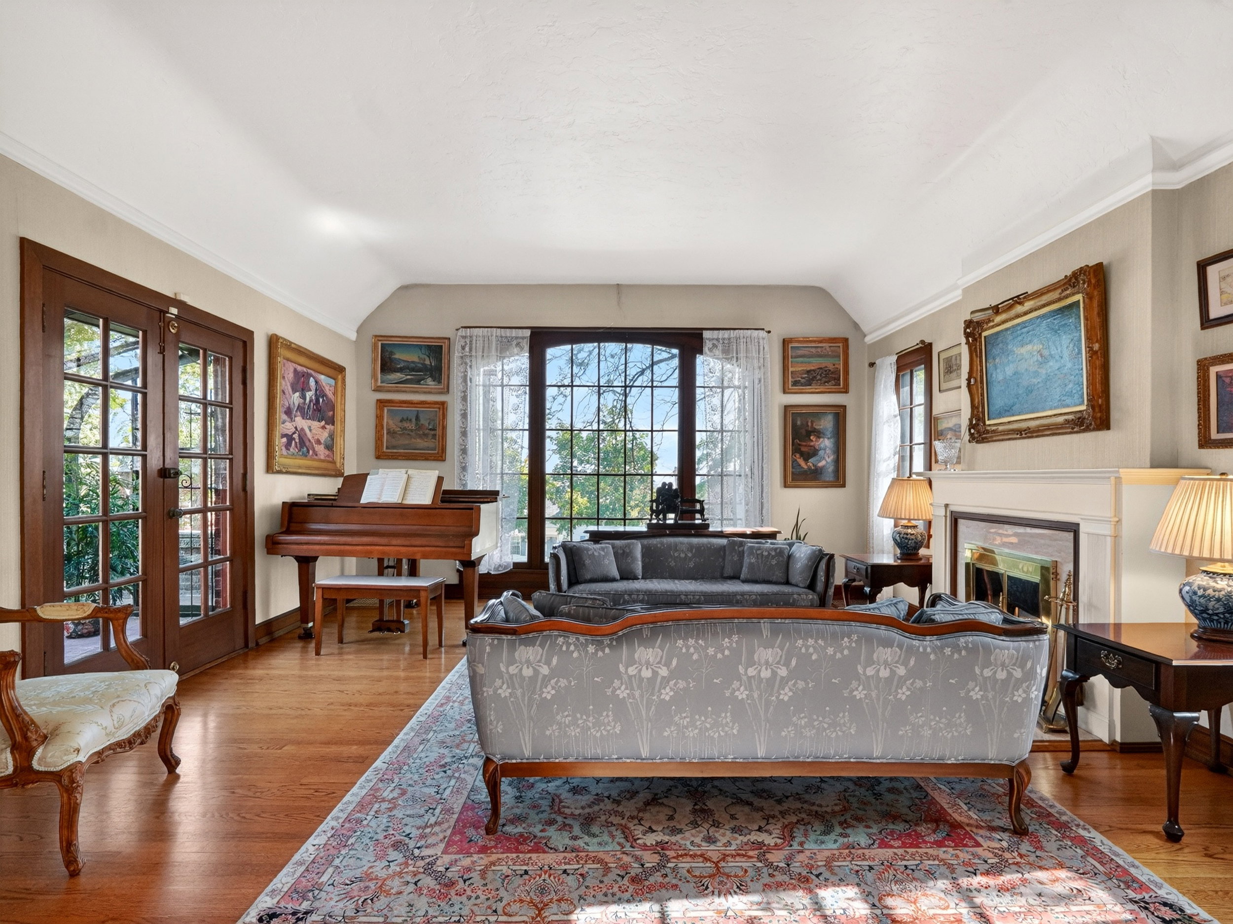 Spacious living area featuring wood-finish flooring, a prominent fireplace with a classic mantel, and crown molding
