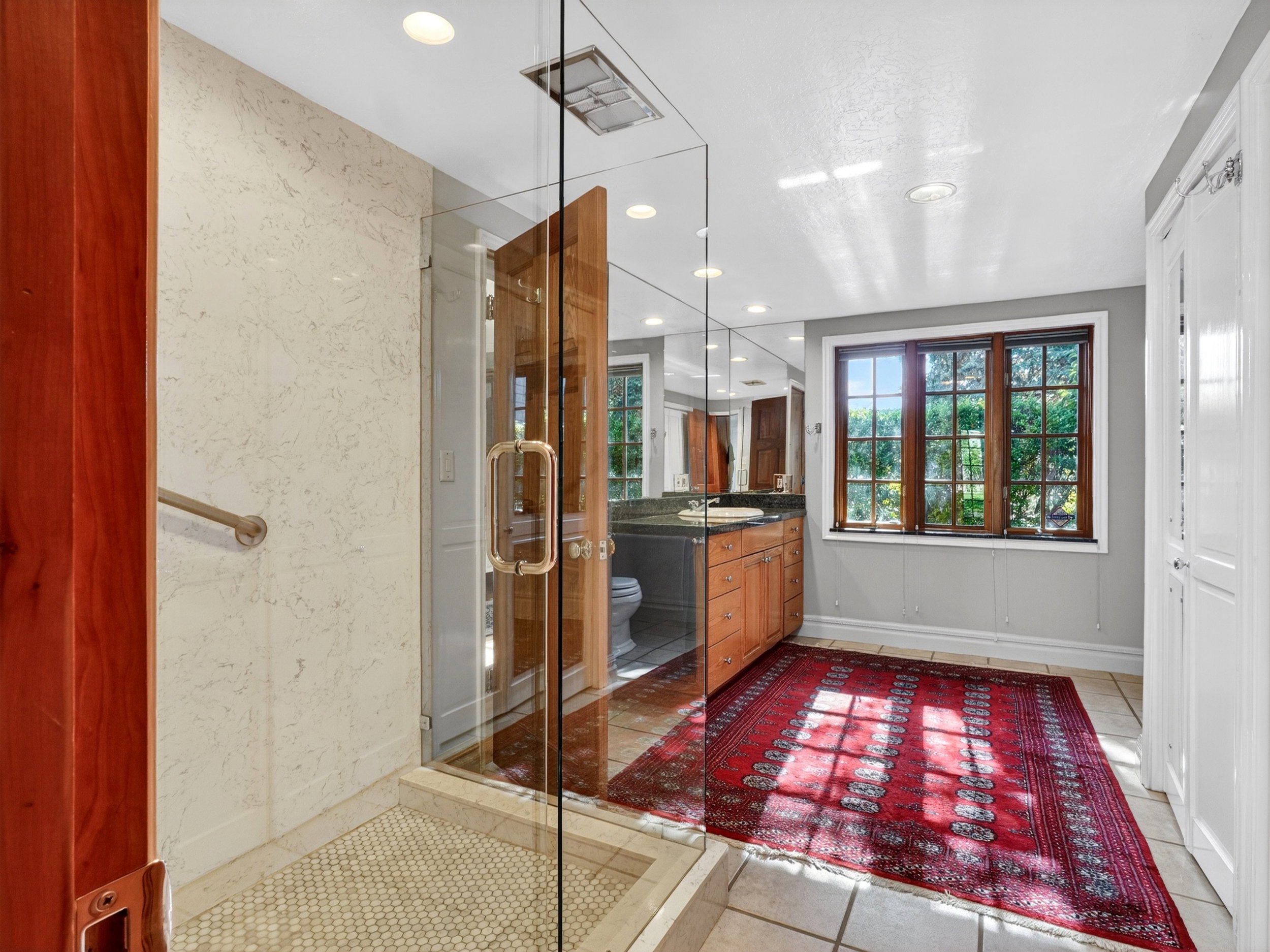Spacious bathroom featuring a glass-enclosed shower with pebble-style flooring.