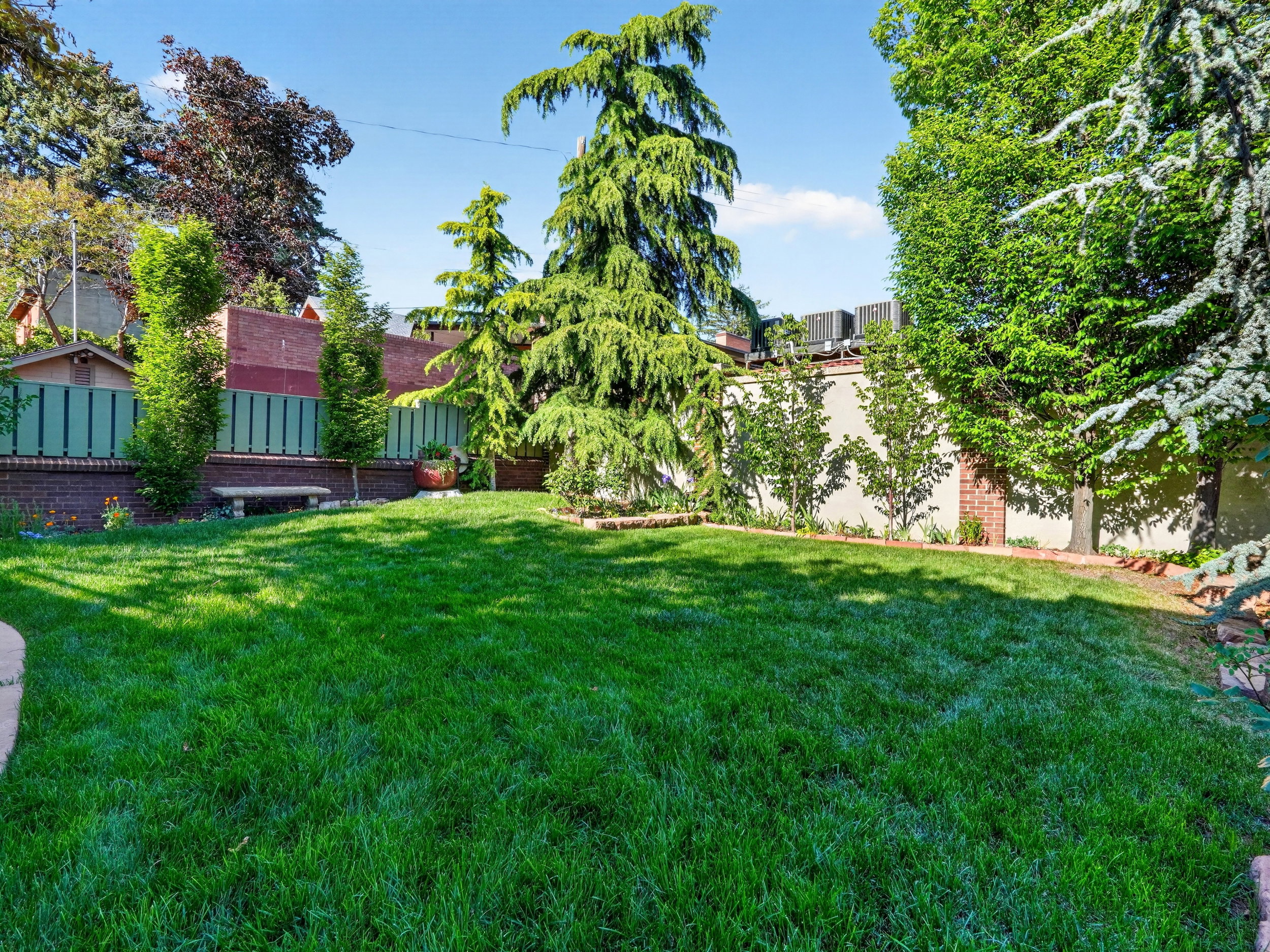 Expansive lawn area featuring mature trees and established perimeter fencing