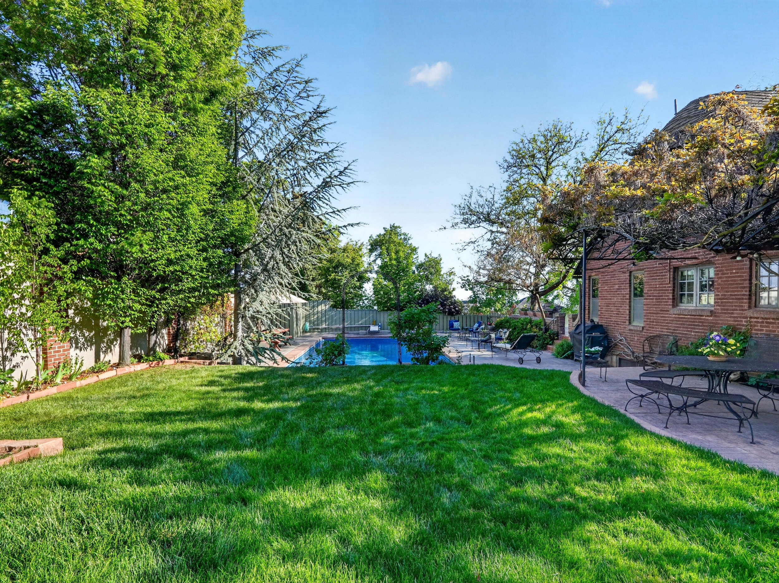 Expansive green lawn and a curved paver patio with a brick exterior