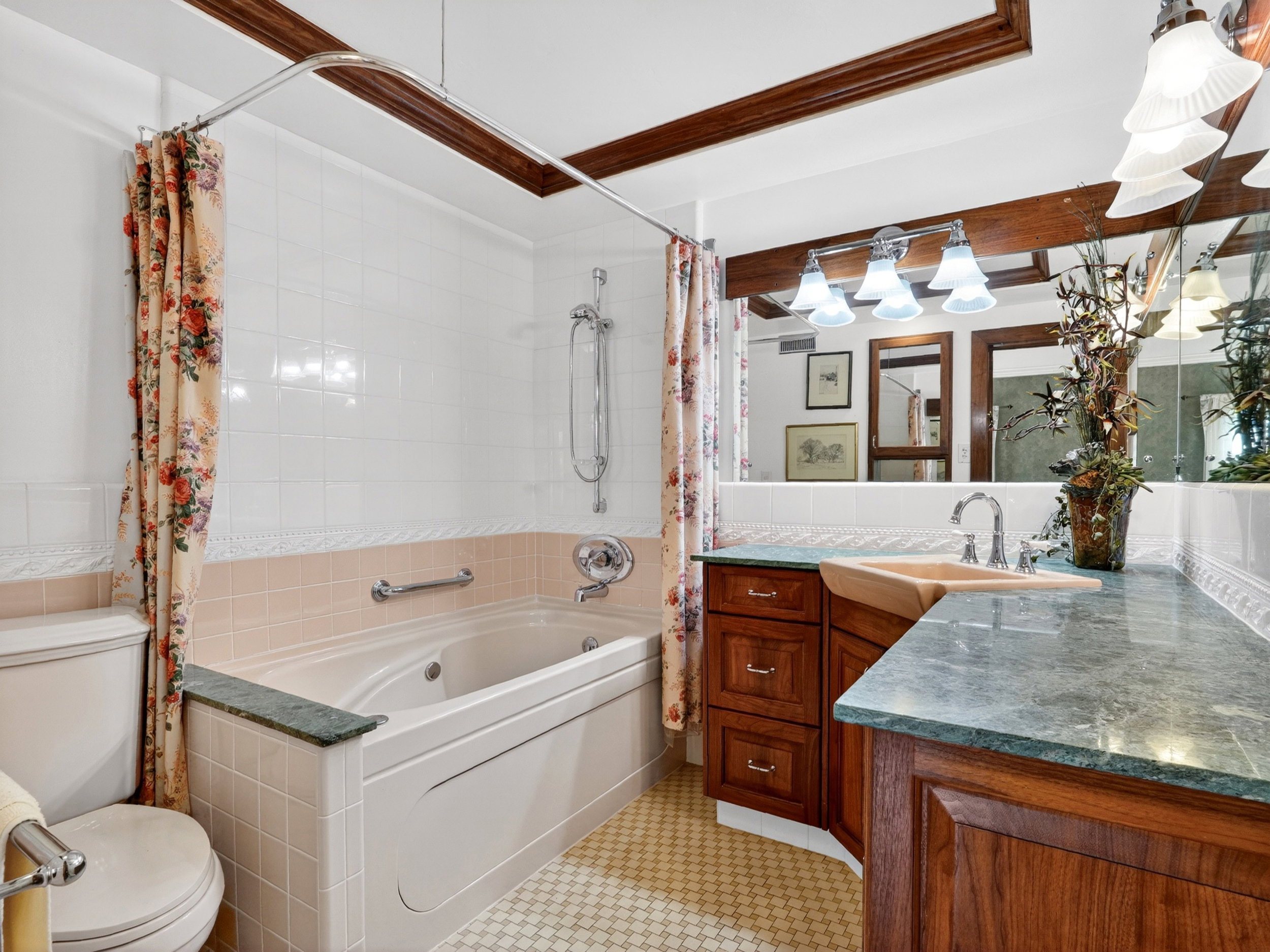 Bathroom featuring a jetted tub, wood-finish vanity with an integrated sink, polished chrome fixtures, and a large wall mirror