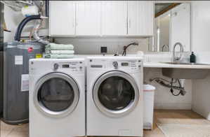 Dedicated laundry area featuring a utility sink, white upper cabinetry, and a countertop space
