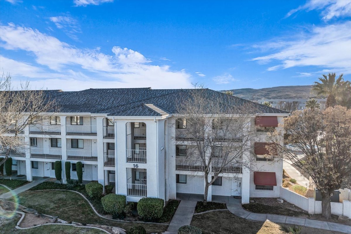 Multi-story building featuring white stucco exterior, dark shingle roof, and individual balconies with white railings