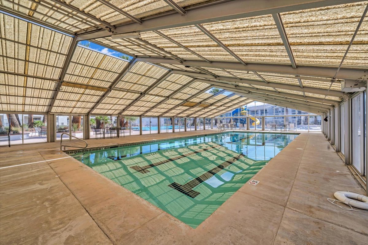 Enclosed swimming pool facility featuring a translucent slatted roof, concrete decking, and a lap lane marked pool