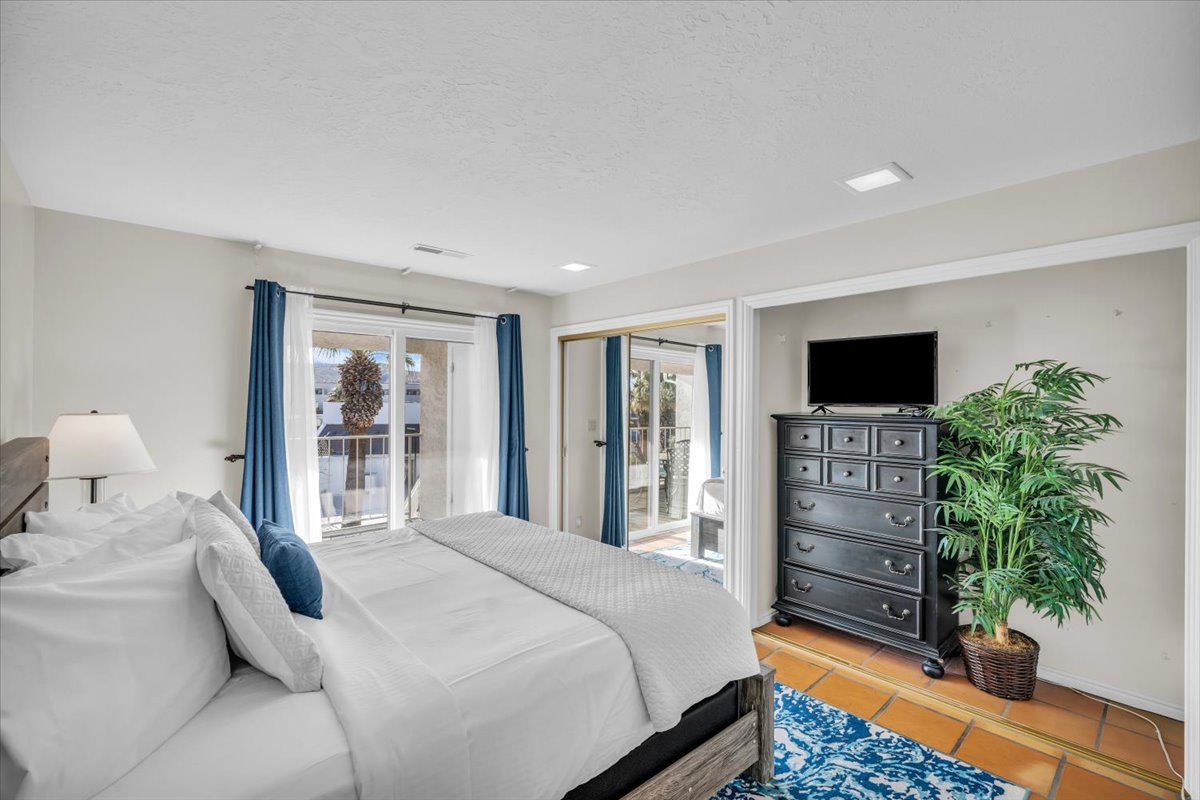 Bright sleeping area featuring sliding glass doors, balcony access, recessed lighting, and tile flooring