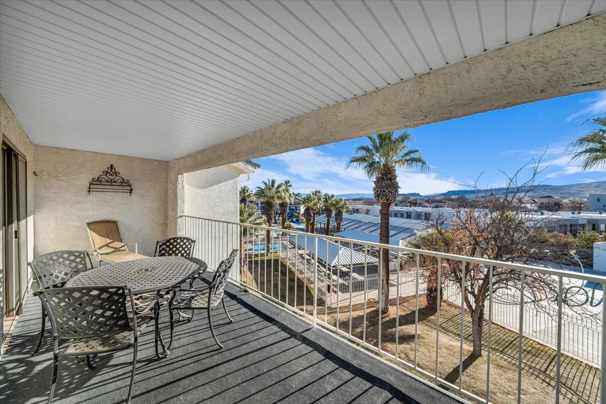 Private balcony with textured wall finish and a slatted ceiling, offering an outdoor living space with surrounding foliage and distant natural scenery