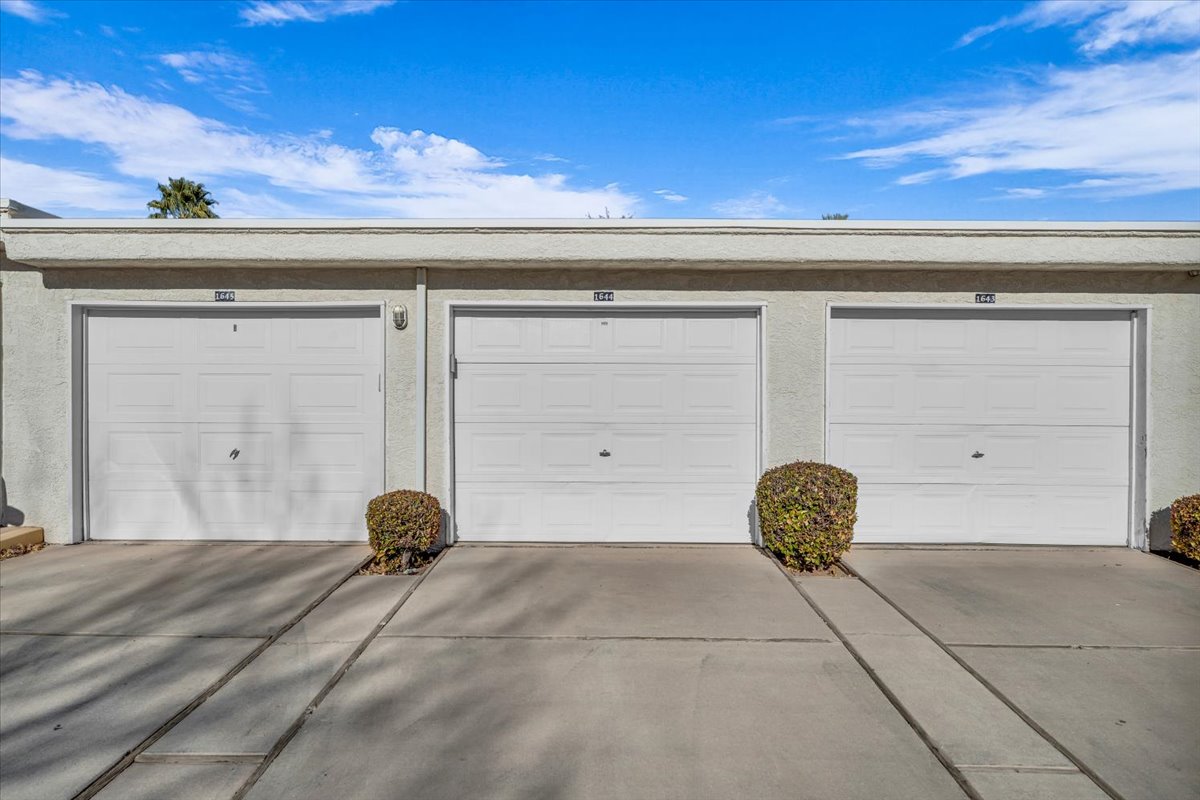 Three individual garage doors with textured finishes and exterior lighting fixtures