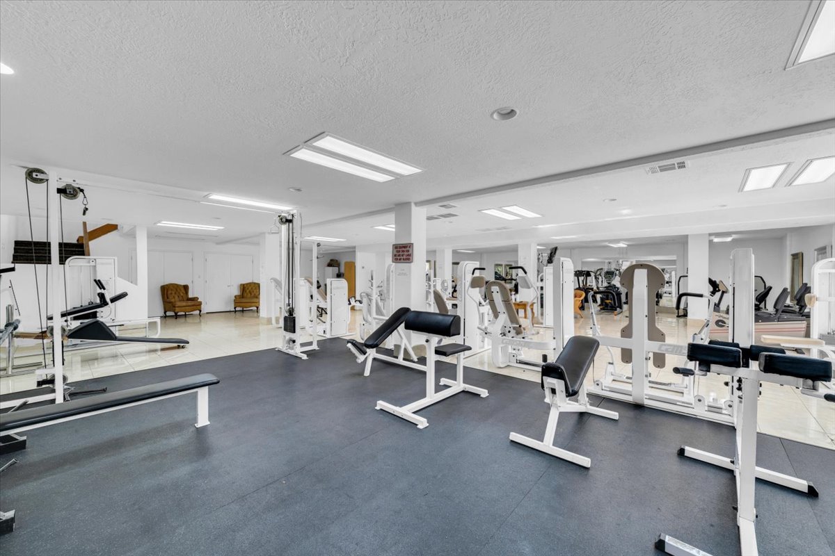 Spacious fitness center featuring a variety of exercise equipment, mirrored walls, and recessed lighting
