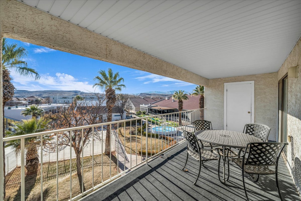 Covered balcony with textured stucco walls, white railing, and a desert landscape background