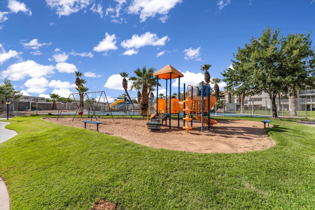 Outdoor recreational area featuring a playground with swings, slides, and climbing structures on a sand base