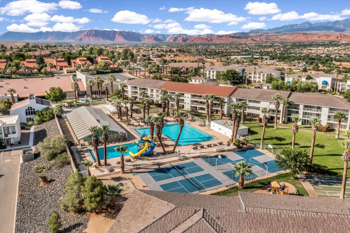 Community amenities featuring multiple swimming pools, a water slide, tennis courts, and mature palm landscaping