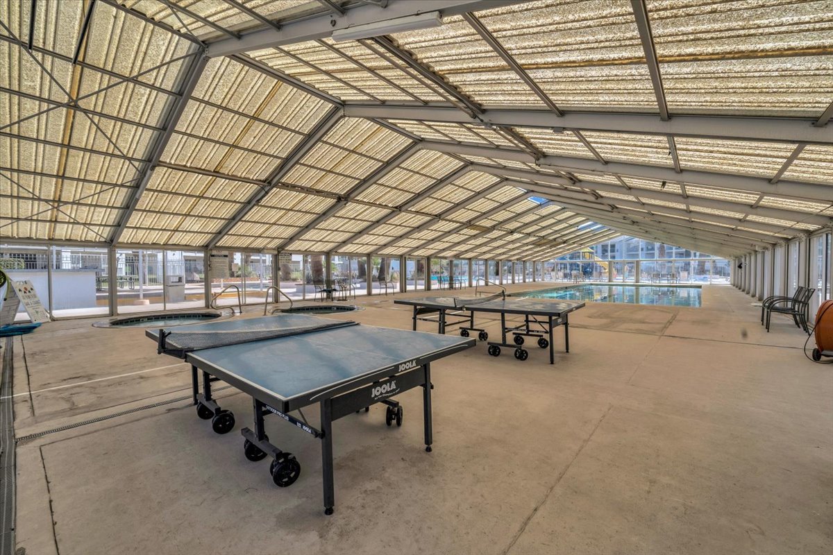 Indoor recreational area featuring a translucent vaulted ceiling, concrete flooring, and a full-size swimming pool