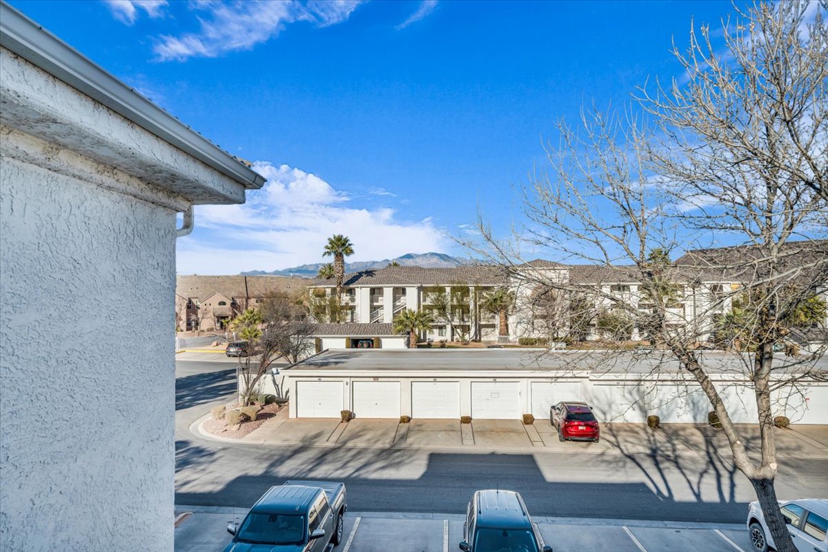 Exterior stucco finish with white gutters, offering a surrounding of multi-story buildings and a mountainous backdrop