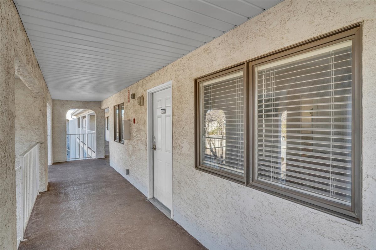 Covered exterior walkway featuring stucco walls and a white paneled ceiling
