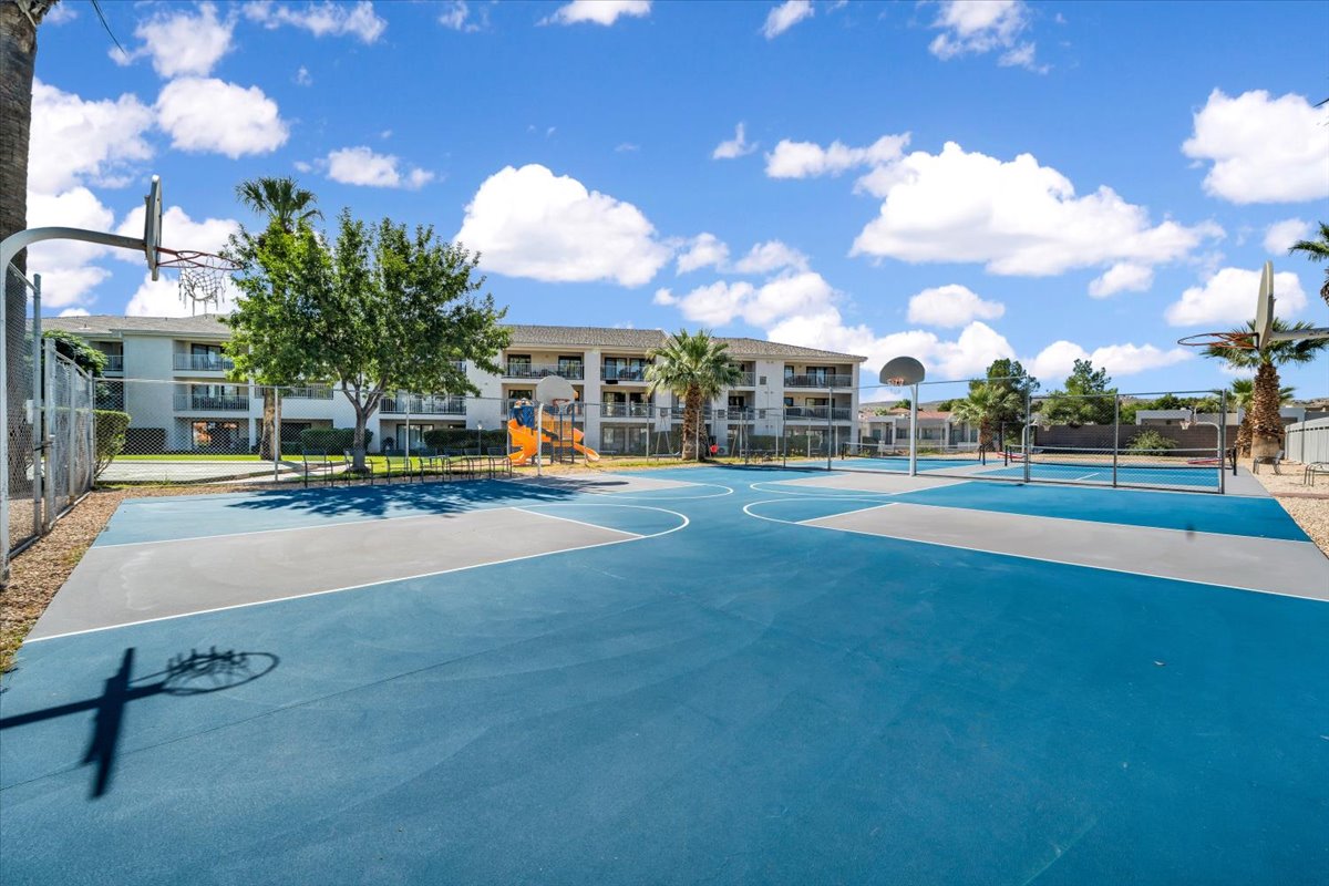 Multi-sport court featuring blue and grey surfacing, two basketball hoops, and a volleyball net
