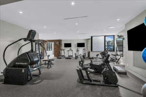 Dedicated fitness room featuring recessed lighting, durable rubber flooring, multiple flat-screen televisions, and large windows
