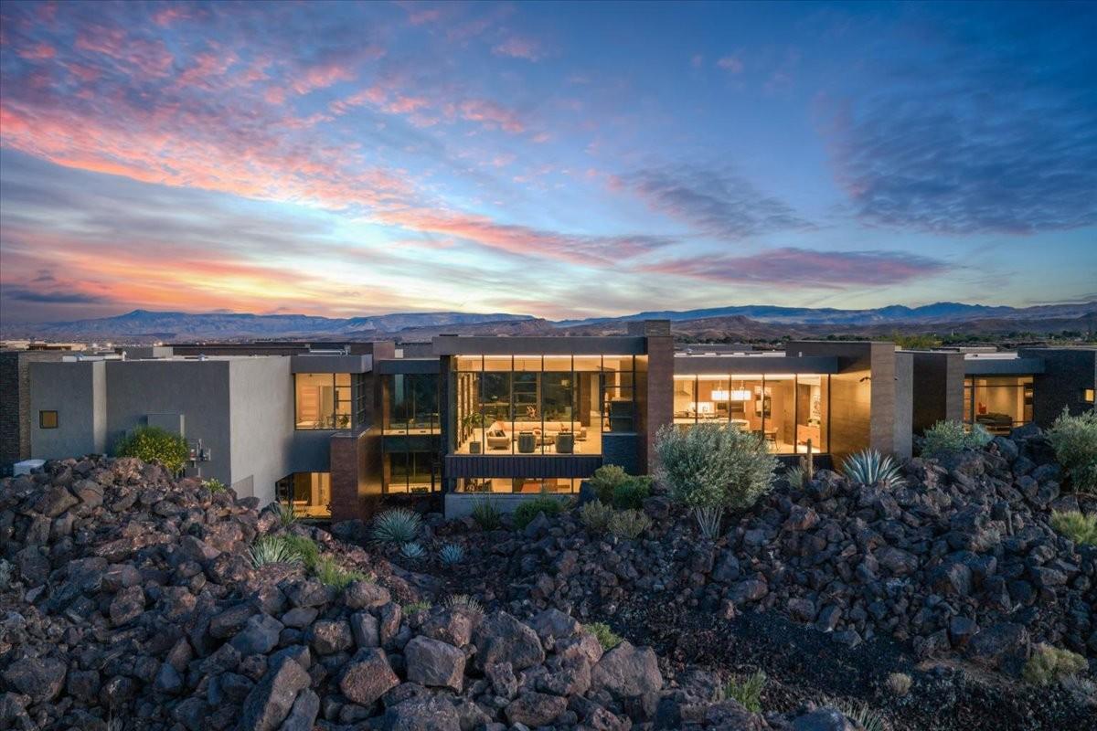 Contemporary architecture featuring extensive floor-to-ceiling windows, multiple balconies, a flat roofline, and a stucco exterior with stone accents