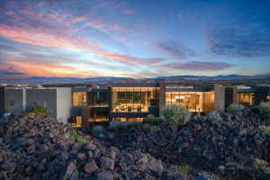 Contemporary architecture featuring extensive floor-to-ceiling windows, multiple balconies, a flat roofline, and a stucco exterior with stone accents