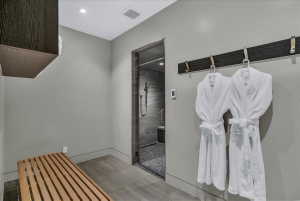 Spa-inspired bathroom featuring a glass-enclosed shower, wood-finish flooring, recessed lighting, and a built-in wooden slat bench