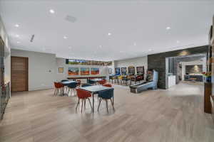 Spacious recreation room featuring large format tile flooring, recessed lighting, and a built-in wet bar with stainless steel appliances