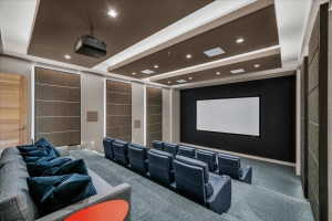 Dedicated home theater featuring tiered seating, a large projection screen, recessed ceiling lighting, and acoustic wall paneling