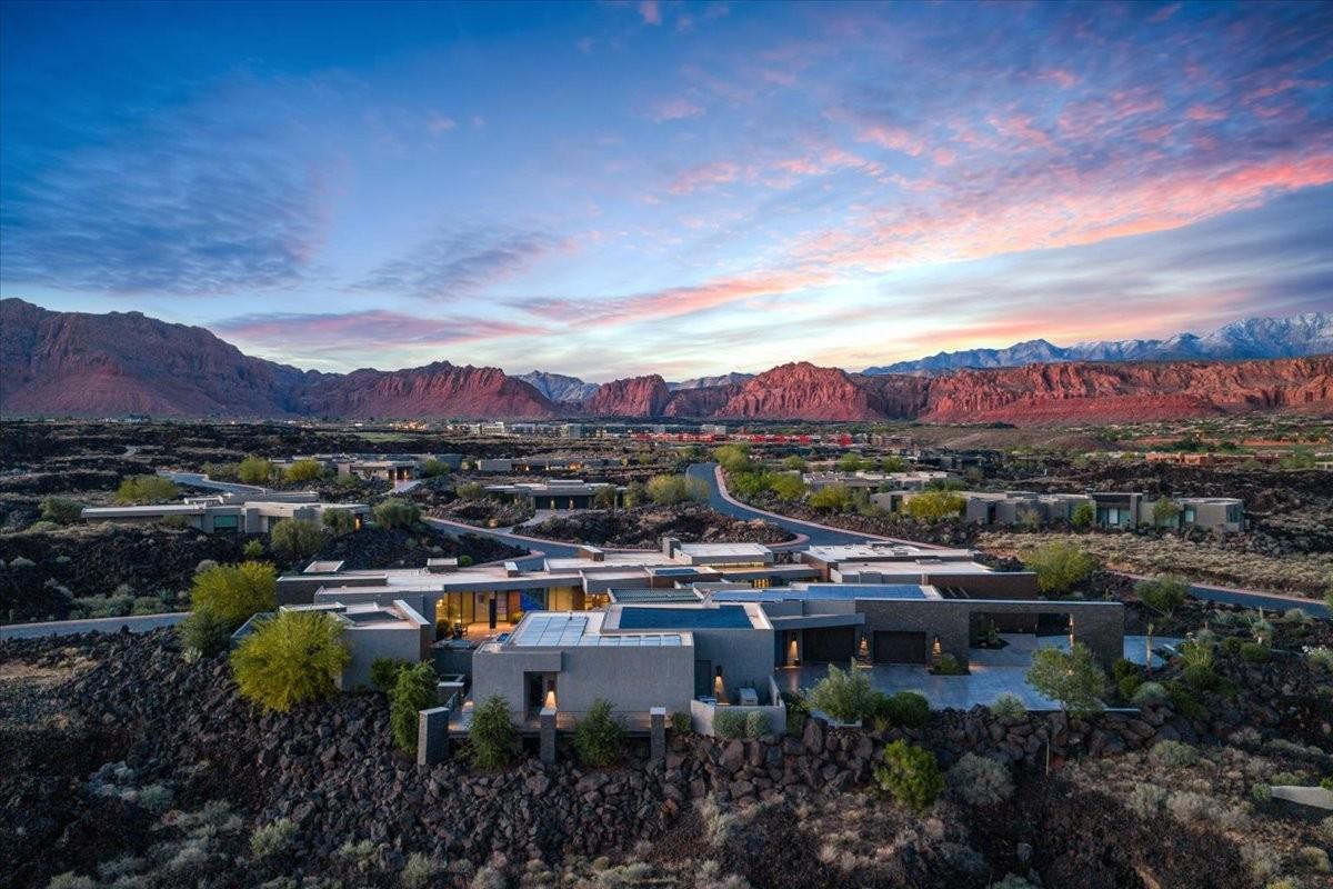 Expansive modern residence featuring a flat roofline, integrated solar panels, and a concrete driveway