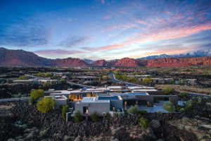 Expansive modern residence featuring a flat roofline, integrated solar panels, and a concrete driveway