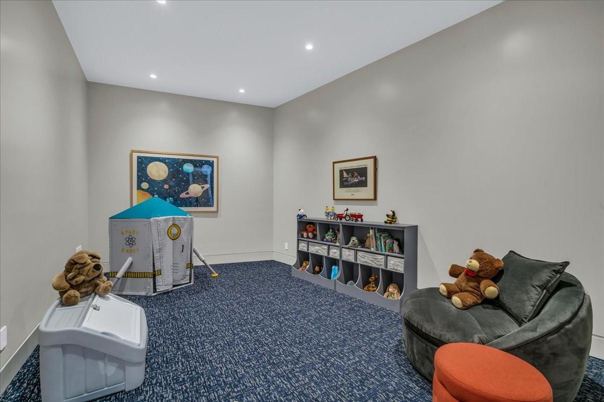 Spacious room featuring neutral painted walls, recessed lighting, blue patterned carpeting, and white baseboards