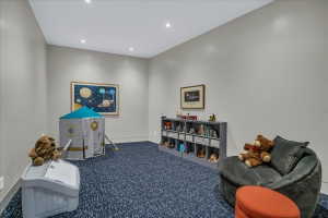 Spacious room featuring neutral painted walls, recessed lighting, blue patterned carpeting, and white baseboards