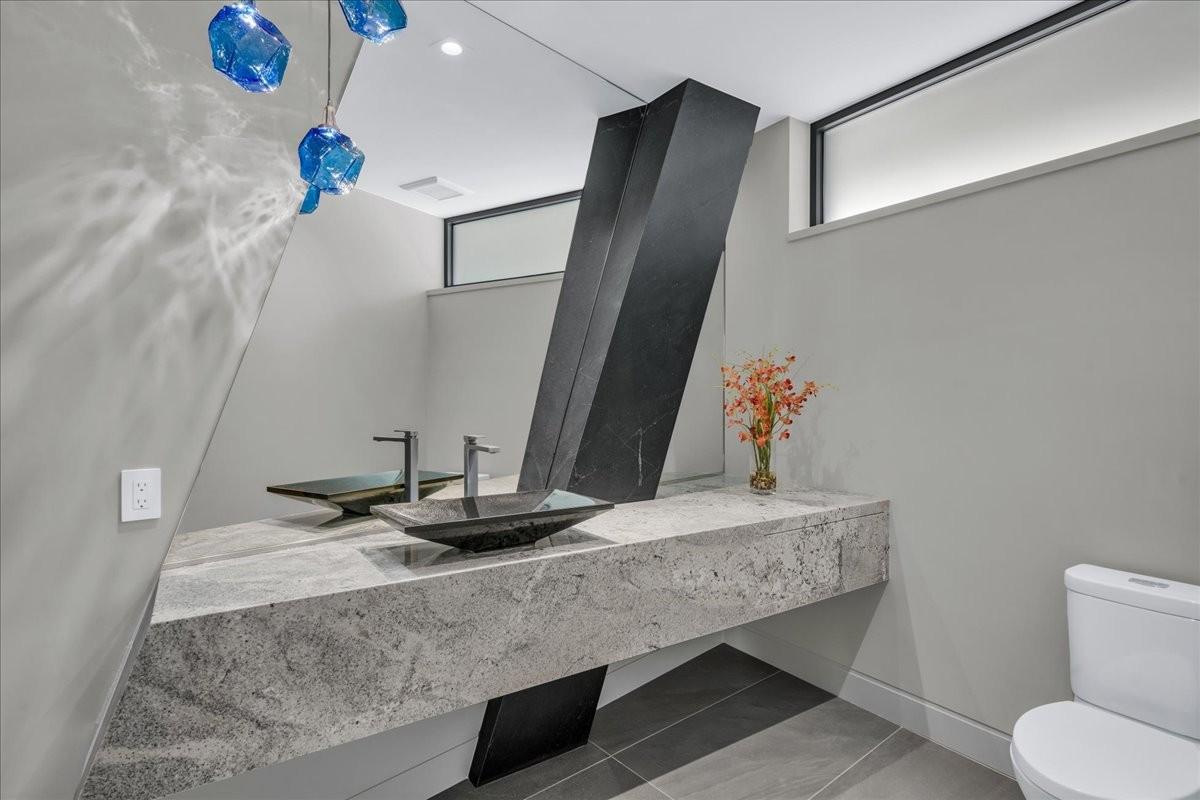 Modern bathroom with a floating stone vanity, twin vessel sinks, and integrated wall mirror