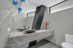 Modern bathroom with a floating stone vanity, twin vessel sinks, and integrated wall mirror