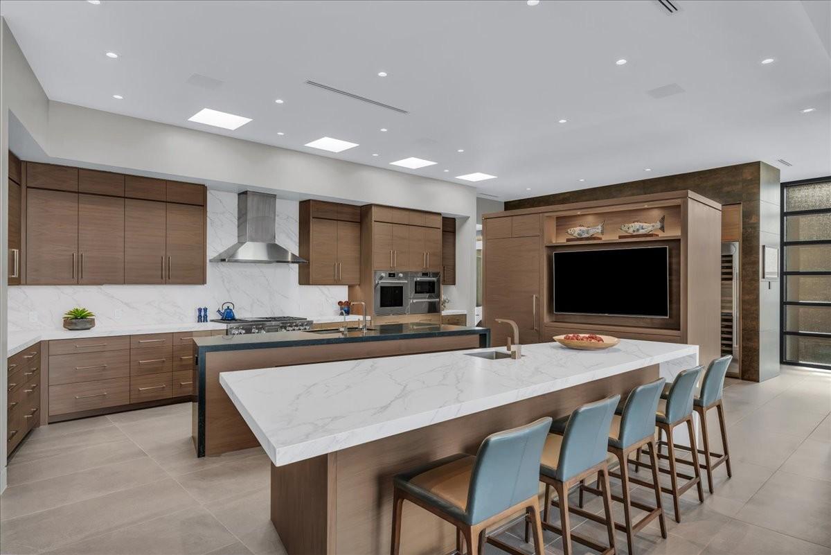 Modern kitchen featuring wood cabinetry, white stone countertops, and integrated stainless steel appliances