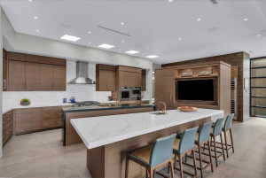 Modern kitchen featuring wood cabinetry, white stone countertops, and integrated stainless steel appliances