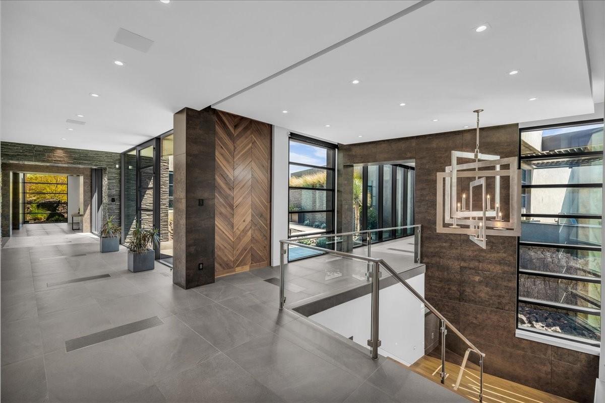 Contemporary interior foyer featuring expansive tile flooring, a geometric chandelier, and a wood-panel accent wall
