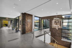 Contemporary interior foyer featuring expansive tile flooring, a geometric chandelier, and a wood-panel accent wall