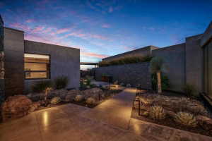 Modern architectural exterior with smooth stucco finish, stone accents, contemporary landscaping, and integrated pathway lighting