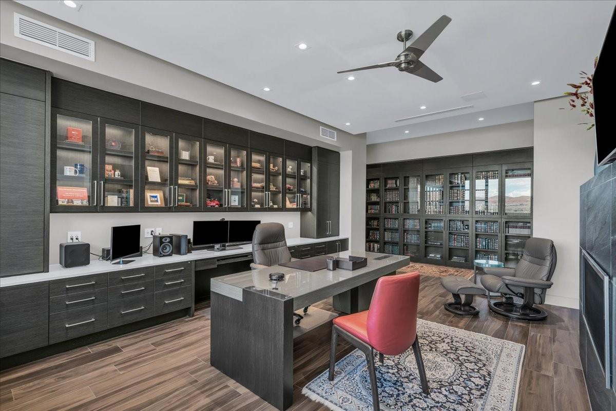 Dedicated office space featuring extensive built-in cabinetry with glass-front uppers and task lighting